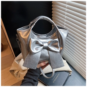 Detailansicht einer silbernen Beuteltasche mit großer Schleife und Metallkette