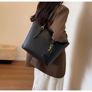 Detail of black matte leather tote bag with gold buckle strap and stylish leather tassel
