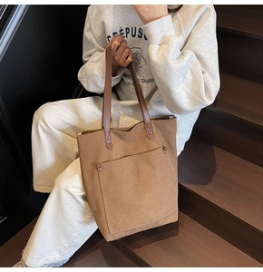 Detalle de un bolso tote de lona marrón con bolsillo frontal y remaches metálicos