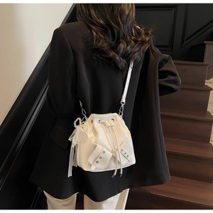 Détail du sac seau blanc à cordon avec boucles décoratives et breloque nœud en perles