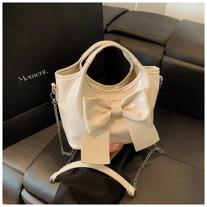 Nahaufnahme der cremefarbenen Schleifen-Handtasche mit Glanzleder und Silberkette
