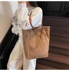 Detalle del bolso tote de lona color caramelo con asas de cuero y cierre de presión
