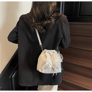 Gros plan d'un sac seau blanc avec cordon de serrage et breloque perle sur un mannequin