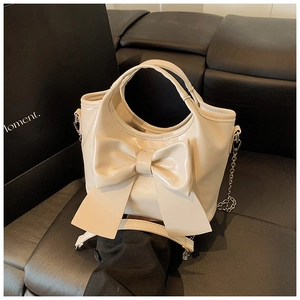 Detail der cremeweißen Leder-Beuteltasche mit großer Schleife und Metallkettenriemen