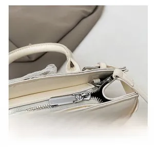 Détail de la fermeture éclair argentée sur un sac seau en similicuir beige doux