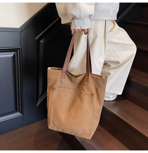 Detalle de bolso tote de lona marrón con bolsillo de remaches y asa de cuero real