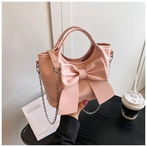 Detail einer rosa Handtasche mit großer Schleife und silbernem Ketten-Schultergurt