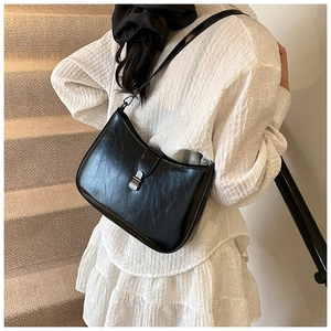 Detail of minimalist black glossy leather underarm bag with silver metallic snap closure
