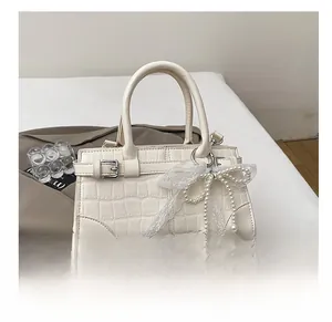 Détail d'un sac seau crème effet crocodile avec un nœud en perles et une boucle métallique