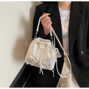 Détail du sac seau blanc avec poches décoratives et accessoire de perles en forme de nœud