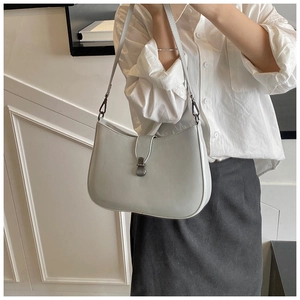 Detail view of light grey minimalist underarm bag with vintage metal buckle worn by model