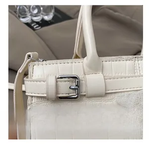 Détail du sac seau blanc cassé avec texture crocodile et boucle en métal argenté