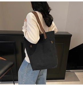 Detalle del bolso tote de lona negra con asas de cuero marrón y remaches vintage de mujer