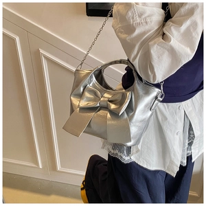 Detail der silbernen Metallic-Handtasche mit großer Schleife und eleganter Metallkette