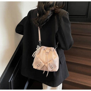 Détail du sac seau rose avec breloque perle et cordon de serrage sur un blazer