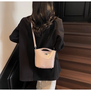 Dettaglio di una borsa a secchiello rosa chiaro con cuciture trapuntate e fibbia