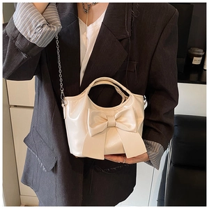Detail der cremefarbenen Beuteltasche mit großer Schleife und silbernem Kettenriemen