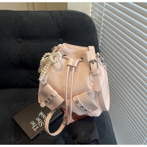 Détail du sac seau rose clair à cordon avec pendentif nœud perlé et poche latérale