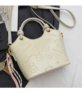 Detail view of cream bucket bag with embossed cartoon patterns and golden hardware