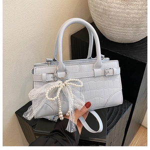 Détail du sac seau bleu clair à motif crocodile avec nœud en dentelle et perles