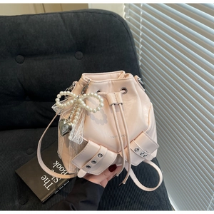 Détail du sac seau rose avec nœud perlé, dentelle et pendentif en forme de cœur