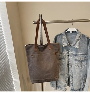 Detalle del bolso tote de lona con asas de cuero marrón y remaches de estilo vintage