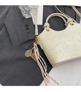 Close-up of cream embossed bucket bag with cute cartoon patterns and decorative charms