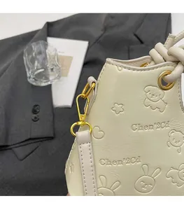 Detailed view of the debossed cartoon patterns and premium gold hardware on the bucket bag