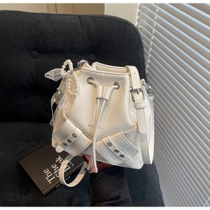 Détail du sac seau en cuir PU blanc avec cordon, poches et breloque cœur en perles