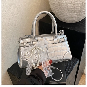 Détails du sac seau argenté à motif crocodile avec dentelle blanche et perles décoratives