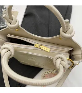 Close-up of cream bucket bag with embossed rabbit patterns and golden zipper closure