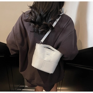 Borsa a secchiello bianca trapuntata con tracolla a catena indossata da una modella