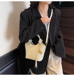 Detail of cream bucket bag with embossed cartoon patterns and decorative silk scarf