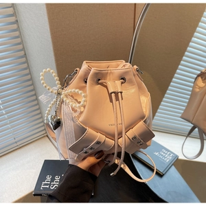 Détails du sac seau rose à cordon avec nœud en perles et pendentif cœur argenté