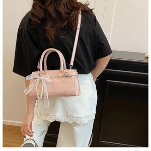 Sac seau rose motif crocodile avec nœud en dentelle et perles porté par un mannequin