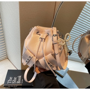 Détail du sac seau rose à cordon avec nœud en perles et texture de cuir poli