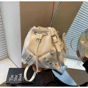 Détail du sac seau blanc cassé avec fermeture à cordon et breloque en perles et dentelle