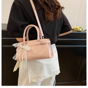 Détail latéral du sac seau rose motif crocodile avec perles et nœud en dentelle
