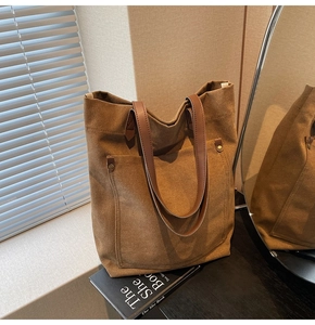 Primer plano de bolso tote de lona vintage con asas de cuero y remaches metálicos