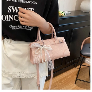 Vue détaillée du sac seau rose gaufré crocodile avec pendentif nœud en dentelle perle