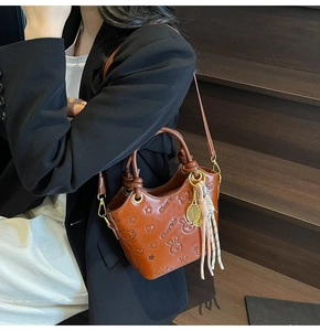 Detail of vintage brown bucket bag featuring embossed cartoon motifs and tennis racket charm