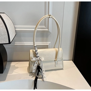 Detail of cream shoulder bag with logo embossing and decorative striped silk scarf accessory