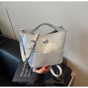 Dettaglio della borsa a secchiello trapuntata celeste con placca logo e catena