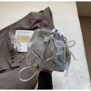 Détail du sac seau bleu clair avec fermeture à cordon et grand nœud en perles
