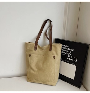 Detalle de bolso tote de lona vintage con bolsillo delantero y asas de cuero marrón
