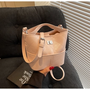 Dettaglio di una borsa a secchiello rosa trapuntata con chiusura argento e trama in pelle PU