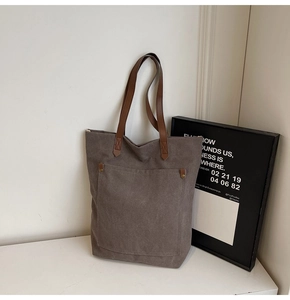 Detalle del bolso tote de lona taupe con correas de cuero sintético marrón y remaches