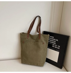 Primer plano de bolso tote de lona verde militar con asas de cuero marrón y remaches
