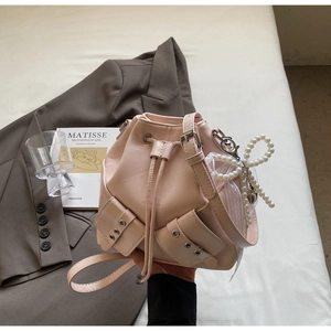 Détail du sac seau en cuir rose pâle avec breloque nœud en perles et doubles poches