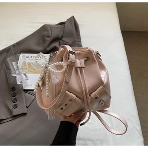 Détail du sac seau rose clair avec nœud en perles, dentelle et fermeture par cordon